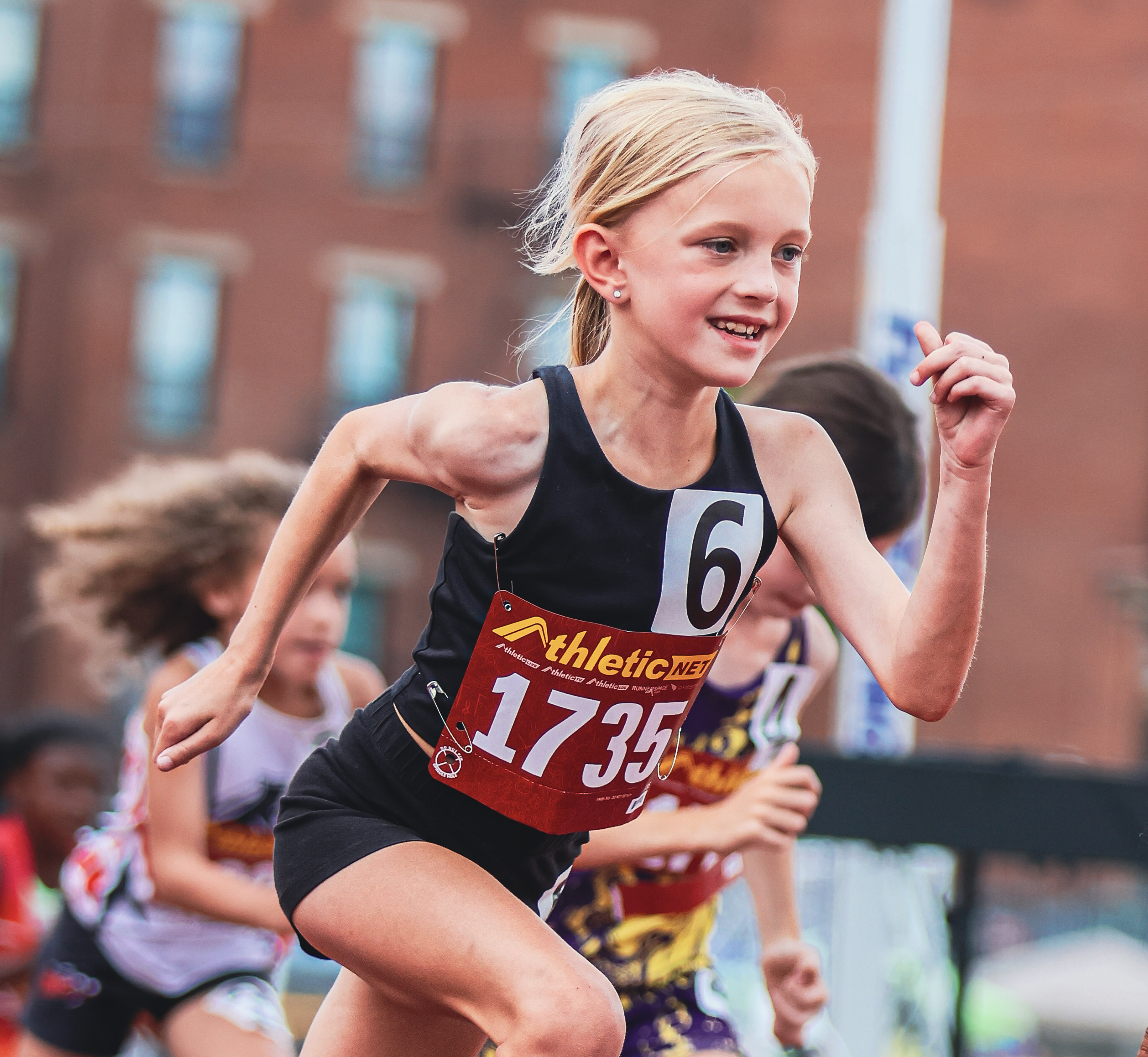 Young runner grins as she begins her race.
